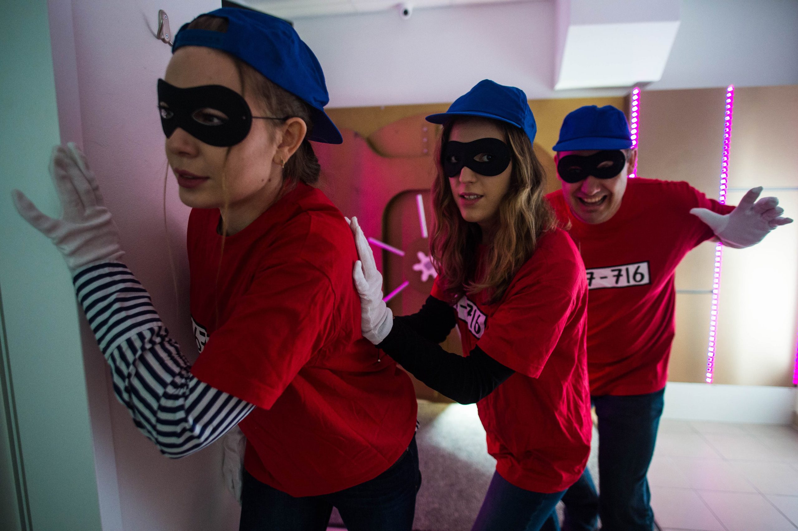 Drei Person mit schwarzer Augenmaske und roten Shirts schleichen sich an im Exit Room Der Tresor von Time-Busters Wien